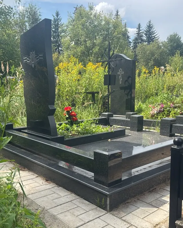 Памятник из чёрного гранита с воинской символикой и надгробной плитой